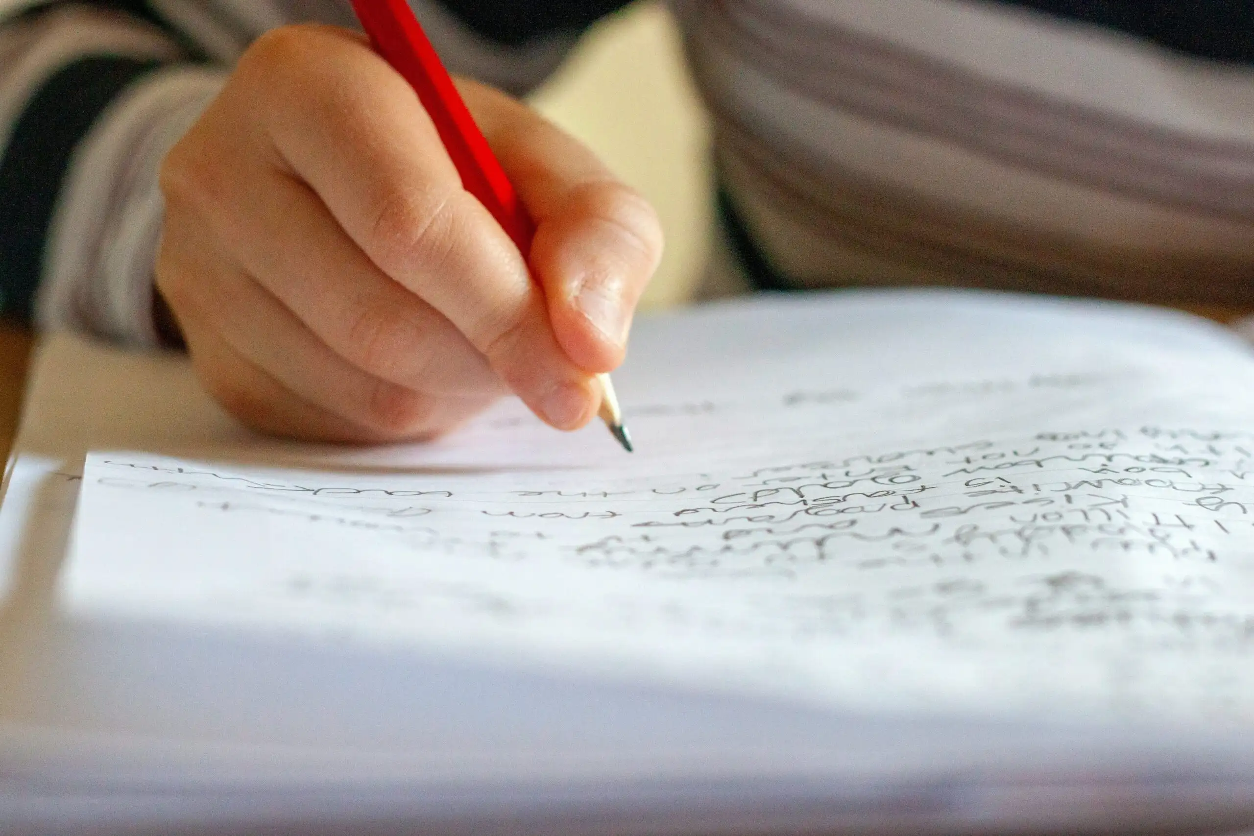 Main écrivant au crayon sur une feuille d’exercices