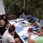 Groupe Erasmus en cours de français en plein air, assis à une table.